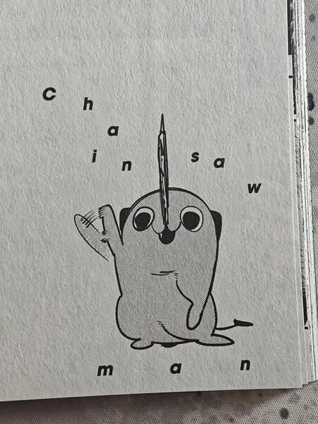 Melnbalts zīmējums ar Pochita tēlu un izkaisītiem burtiem, kas veido vārdus "chainsaw man". (Captioned by AI)